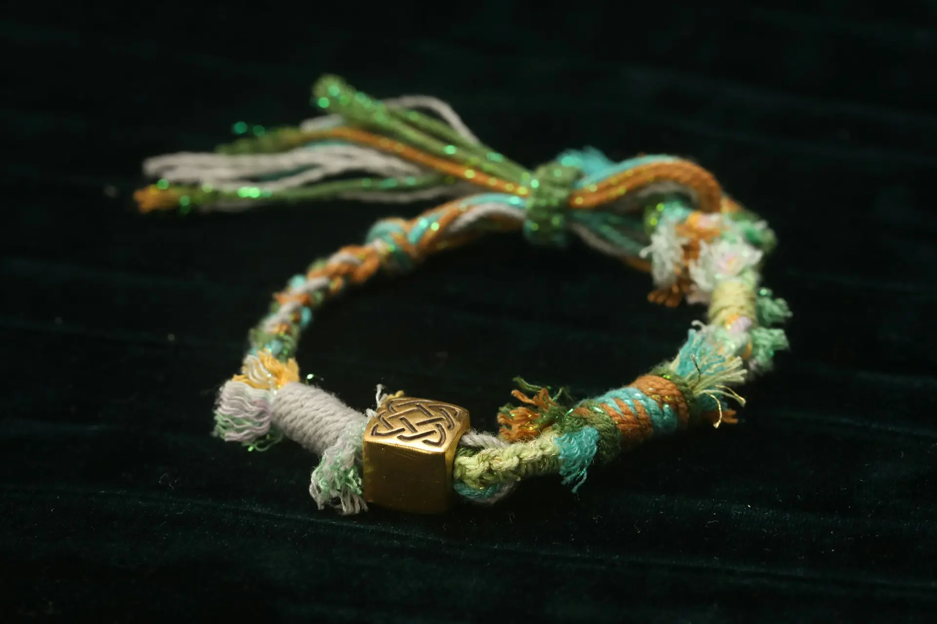 Handmade bracelet with golden bead on dark background